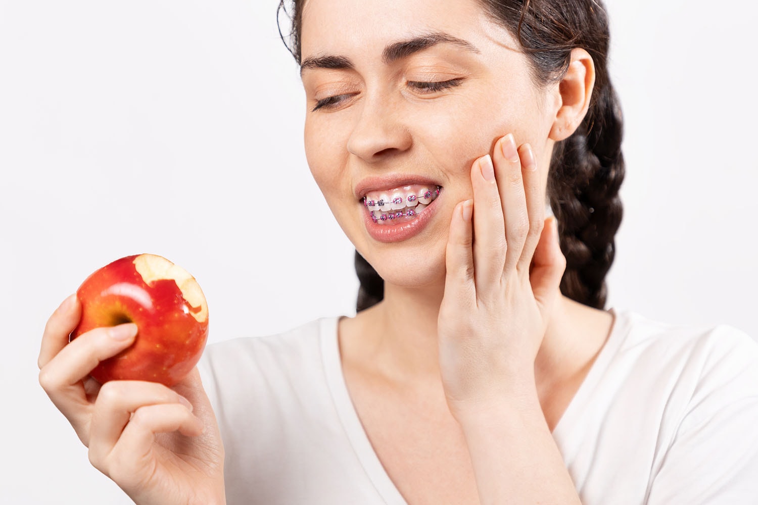 Mädchen mit feste Zahnspangen hat schmerzen nachdem Sie in einen Apfel gebissen hat